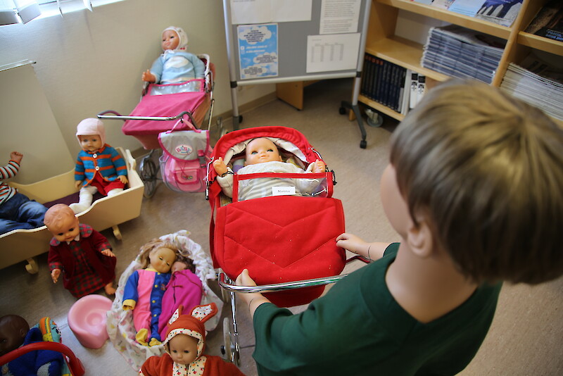 Nukkia on aseteltu ympäri kirjastoa. Esimerkiksi rattailla oleva Nanna-nukke löytyy kirjaston perältä.