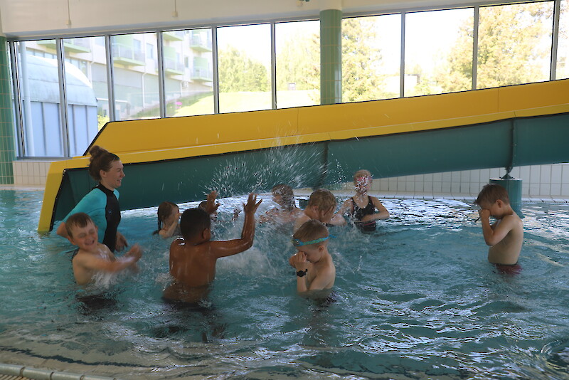 Terveysliikuntakoordinaattori Eeva Lehtiniemi leikittää uimakoululaisia kylpylässä.